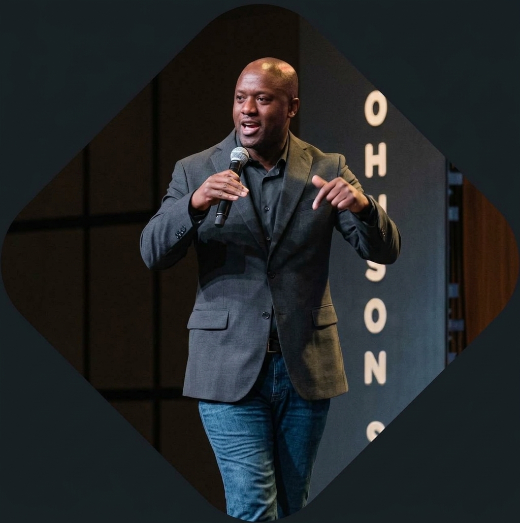 Neco Johnson speaking on stage with a microphone